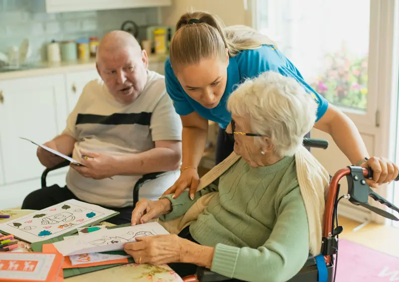 Opatrovateľka pomáha seniorom s kreslením